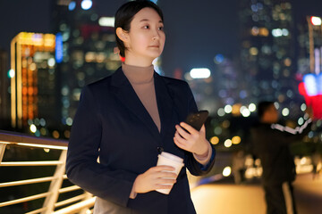 Businesswoman in the City Night with Smartphone