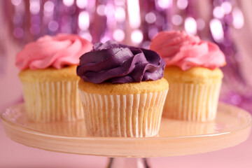 Delicious cupcakes with bright cream on pink background, closeup