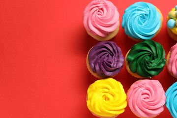 Delicious cupcakes with bright cream on red background, flat lay. Space for text