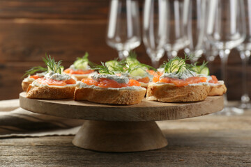 Tasty canapes with salmon, cucumber, cream cheese and dill on wooden table