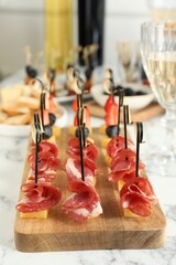 Different tasty canapes on white marble table, closeup