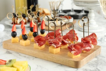 Different tasty canapes on white marble table, closeup