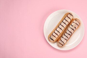 Delicious eclairs covered with glaze on pink background, top view. Space for text