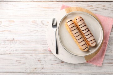 Tasty glazed eclairs served on wooden rustic table, top view. Space for text
