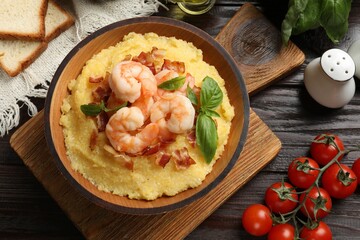Fresh tasty shrimps, bacon, grits and basil in bowl on wooden table, flat lay