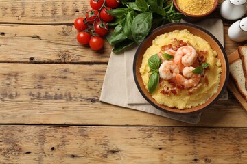 Fresh tasty shrimps, bacon, grits and basil in bowl on wooden table, flat lay. Space for text