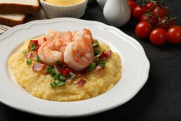 Plate with fresh tasty shrimps, bacon, grits, green onion and pepper on black table, closeup