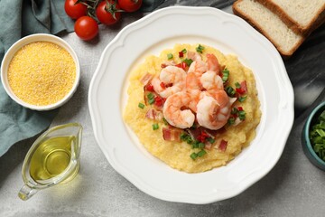 Plate with fresh tasty shrimps, bacon, grits, green onion and pepper on gray textured table, flat lay