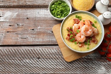 Fresh tasty shrimps, bacon, grits and green onion in bowl on wooden table, flat lay. Space for text