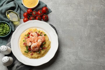 Plate with fresh tasty shrimps, bacon, grits, green onion and pepper on gray textured table, flat...