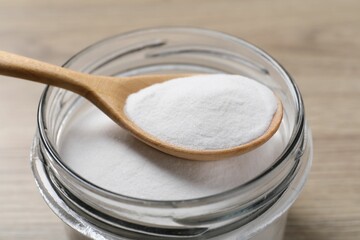 Baking soda in glass jar on wooden table, closeup