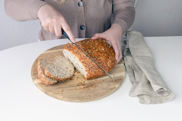 Woman cutting bread on a cutting board.