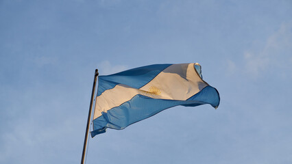 Details of an Argentine flag on a blue sky.