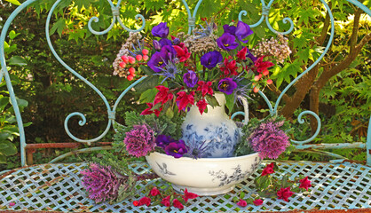 Still life of flowers in a vase on a bench in a garden