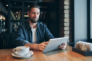 Young man drinking coffee cafe using tablet computer freelancer workplace lunch