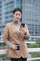 Professional Woman Checking Smartphone with Coffee Outdoors