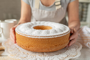 Homemade bundt cake holding by woman´s hands