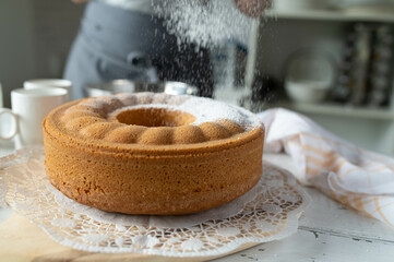 Sprinkling powdered sugar over a fresh baked bundt cake or gugelhupf