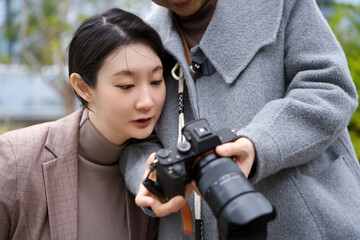 Two Women Reviewing Images on DSLR Camera Outdoors