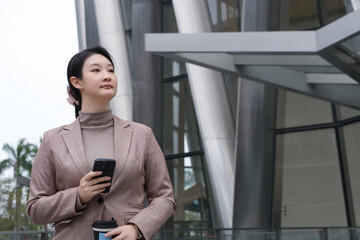 Professional Woman with Smartphone Outside Modern Building