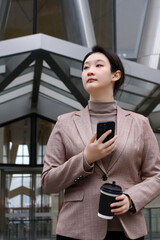 Confident Businesswoman Juggling Coffee and Smartphone