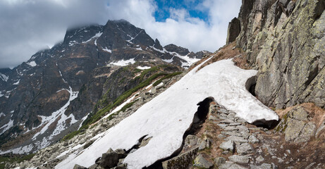 Topniejący śnieg odkrywający znakowany szlak wysokogórski w Tatrach Wysokich.