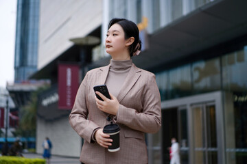 Stylish Businesswoman with Coffee and Smartphone in the City