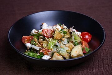 Delicious salad with fresh vegetables and feta cheese on black plate