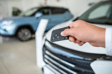  dealer hand holding key against new auto at showroom. success deal