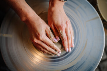 Dobele, Latvia - August 18, 2023 - Close-up of hands shaping wet clay on a pottery wheel, with...