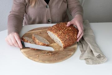 Woman cutting bread on a cutting board.