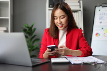 Businesswoman working in the home office is using mobile phone to send messages and chat with colleagues.