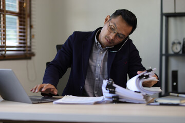 Serious executive businessman is busy with paperwork on the table in the office.