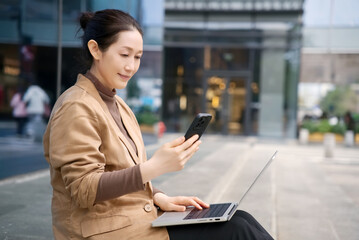 Professional Woman Multitasking with Laptop and Phone