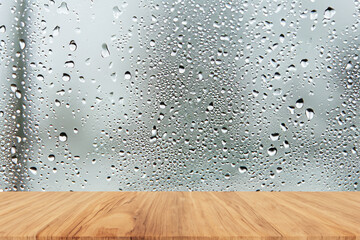 Wooden tabletop on raindrops on clear window - obrazy, fototapety, plakaty