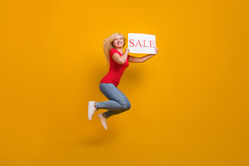 Full length body size photo woman jumping keeping sale card laughing isolated vibrant orange color background