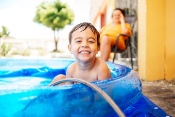 Happy child playing in inflatable home pool in summer. Active outdoor recreation.