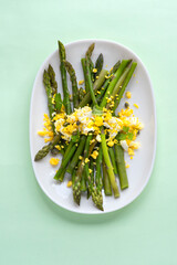 Asparagus salad Mimosa. Spring and Easter salad with grated egg, capers and aromatic dressing. Mint background. Healthy vegetarian balanced recipes for spring, seasonal cuisine