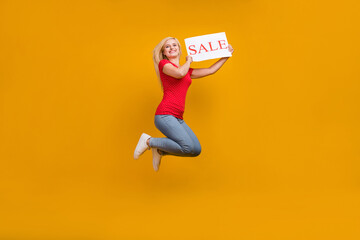 Full length body size photo woman jumping keeping sale card isolated vibrant orange color background