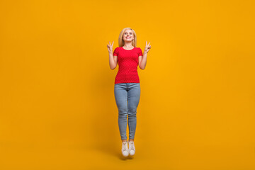 Full length body size photo woman jumping up showing v-sign isolated vibrant orange color background
