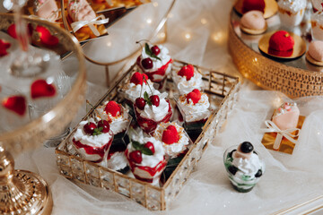A tray of desserts with a variety of flavors and toppings, including a cherry on top. The desserts...