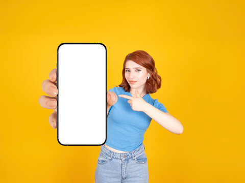Recommending application. Red bob hair caucasian 20s woman holding smartphone close up to camera pointing empty blank white touch screen. Mobile phone mock up advertisement concept idea photo.