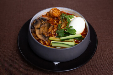 Bowl of spicy Korean ramen with mushrooms, egg, cucumber, and cilantro.
