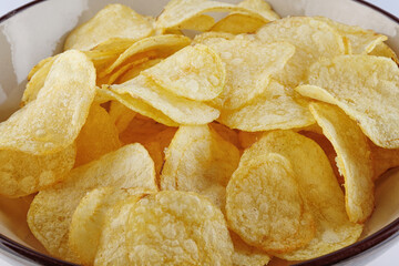Bowl of potato chips on white background.