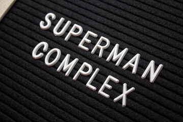 the word superman complex is written on a black letter board