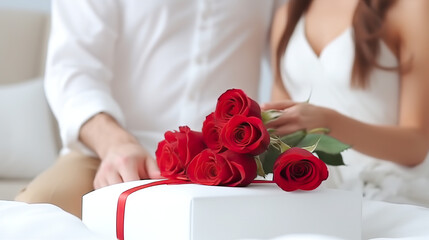 A contented couple holding hands a red rose bouquet and a gift, separated on a white background