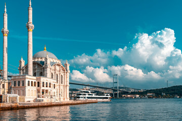 Fototapeta na wymiar A mosque with a blue sky in the background. Ortakoy Mosque, Besiktas Turkey. A mosque in Istanbul with the bridge in the background.