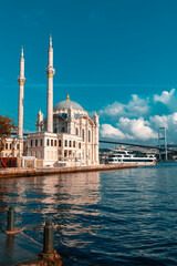 Naklejka premium A mosque with a blue sky in the background. Ortakoy Mosque, Besiktas Turkey. A mosque in Istanbul with the bridge in the background.