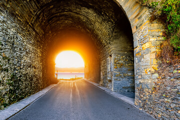 Beautiful road in a rock tunnel with amazing sunset. Road near the lake