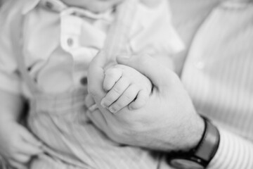 A father is holding his newborn baby son's hand